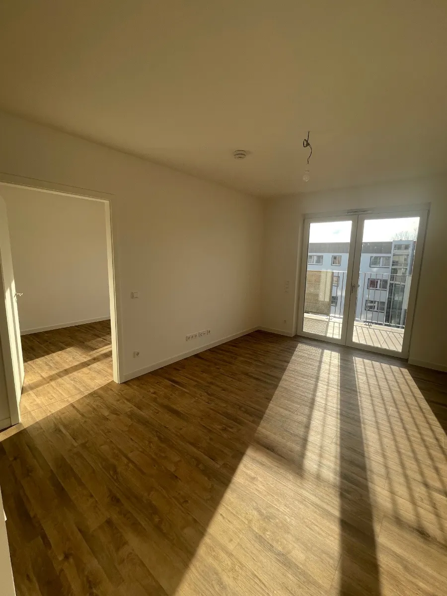 DSW24 – Dresder Servicewohnen GmbH – Augustus Residenz Dresden-Prohlis – Wohnbereich Heller Wohnbereich der Augustus Residenz in Dresden Prohlis mit Zugang zu einem weiteren Zimmer und Fensterfront zum Balkon.