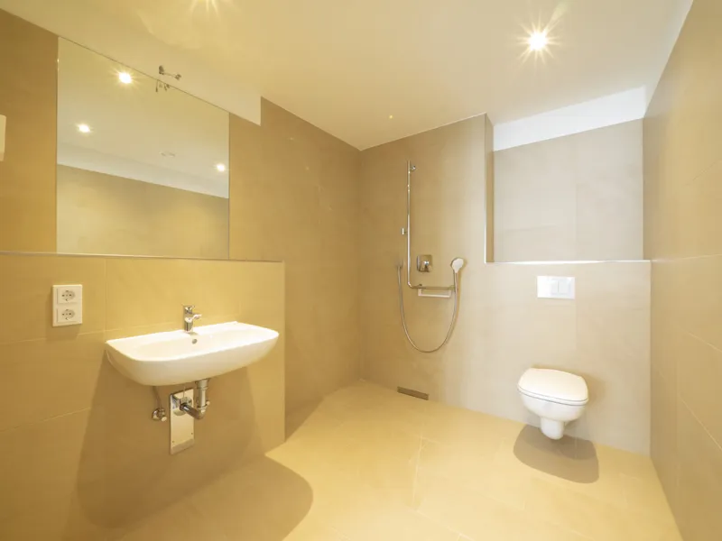 DSW24 – Dresder Servicewohnen GmbH – Laurentii Residenz Meißen – Badbeispiel Beispiel eines Badezimmers der Laurentii Residenz in Meißen mit bodengleicher Dusche, erhöhtem WC und Waschbecken mit Spiegel.