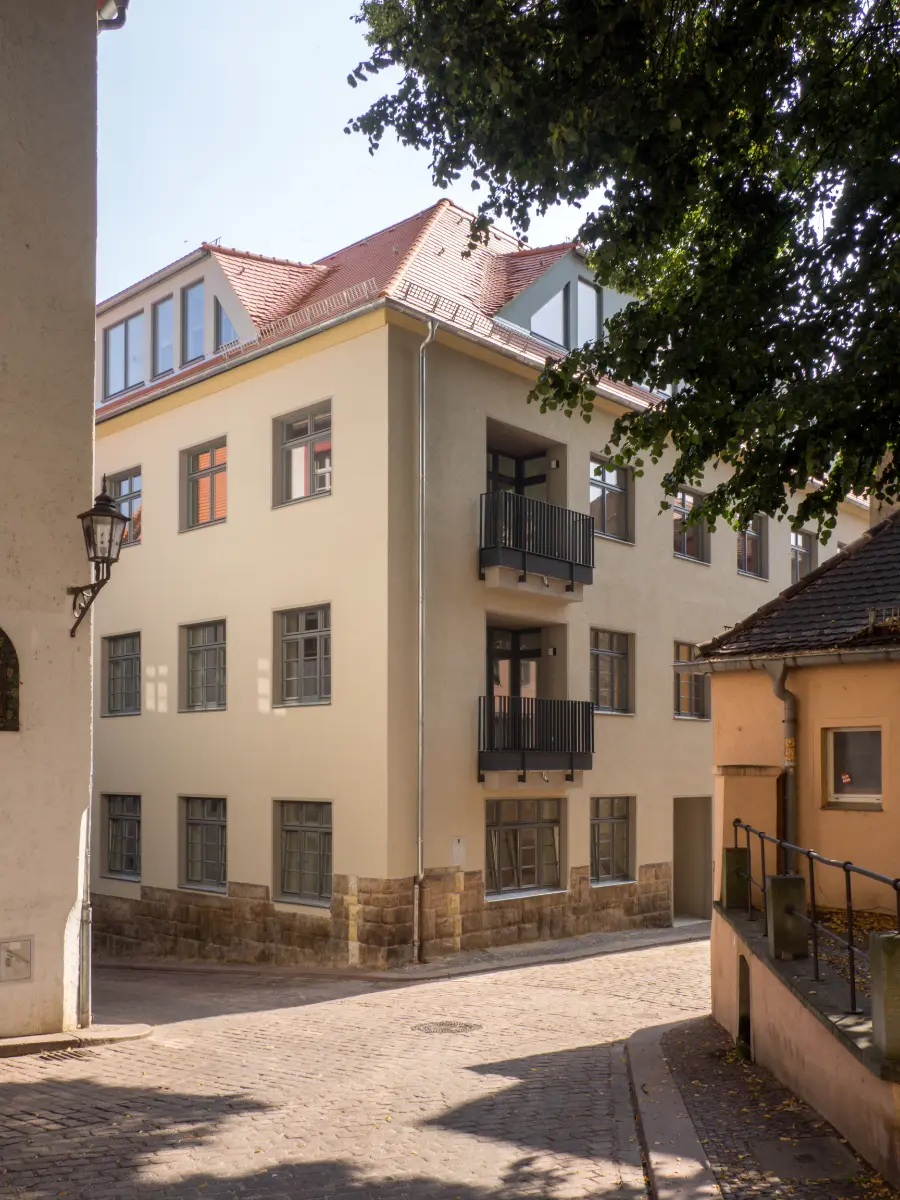 DSW24 – Dresder Servicewohnen GmbH – Laurentii Residenz Meißen – Außenansicht Außenansicht der Laurentii Residenz in Meißen mit modernisierter Fassade und Balkonen an einem gepflasterten Weg,