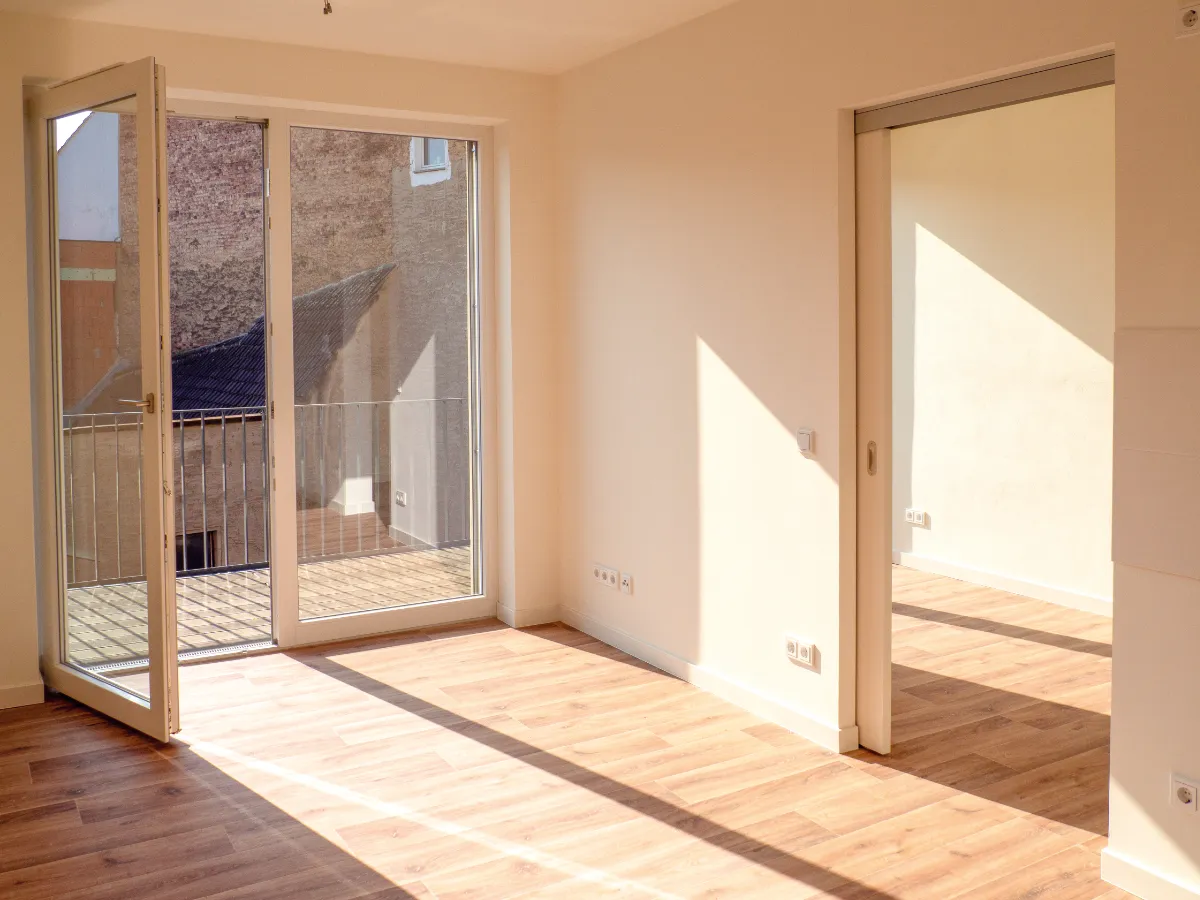 DSW24 – Dresder Servicewohnen GmbH – Laurentii Residenz Meißen – Wohnzimmer mit Balkon Zimmer der Laurentii Residenz in Meißen mit geöffneter Balkontür, Schiebetür ins Nebenzimmer und Vinylboden.