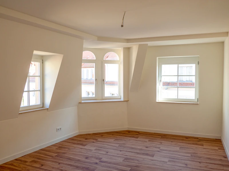 DSW24 – Dresder Servicewohnen GmbH – Laurentii Residenz Meißen – Wohnbereich Wohnung im Dachgeschoss der Laurentii Residenz in Meißen mit drei über Eck angeordneten Fenstern und Vinylboden.