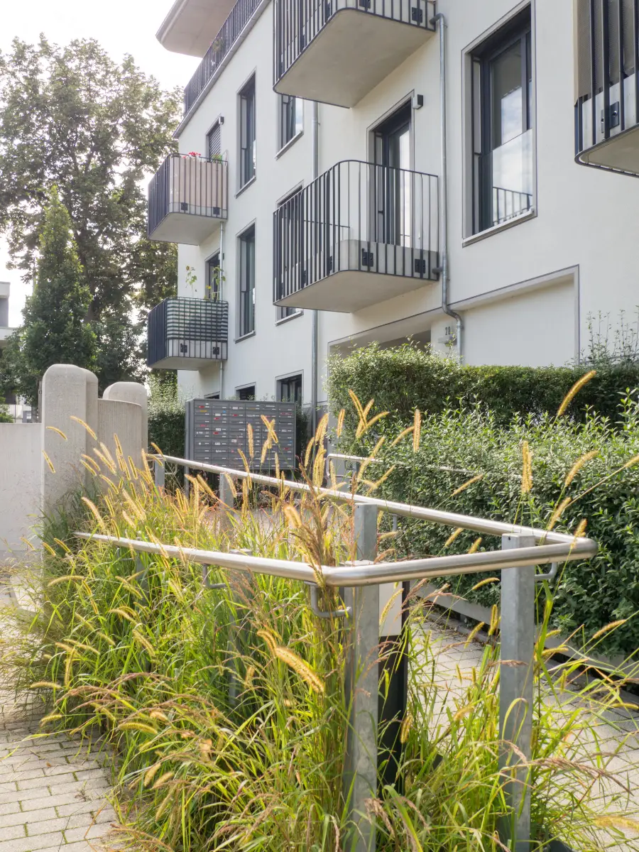 DSW24 – Dresder Servicewohnen GmbH – Rennbahn Residenz Dresden-Seidnitz – Eingangsbereich mit Briefkästen Eingangsbereich der Rennbahn Residenz in Dresden Seidnitz mit Balkonen, Briefkästen und Grünanlage.